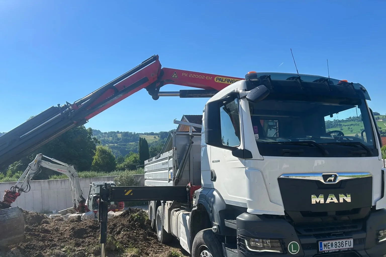 MAN-Kranlastwagen und Takeuchi-Bagger auf einer Baustelle in der Region Luzern