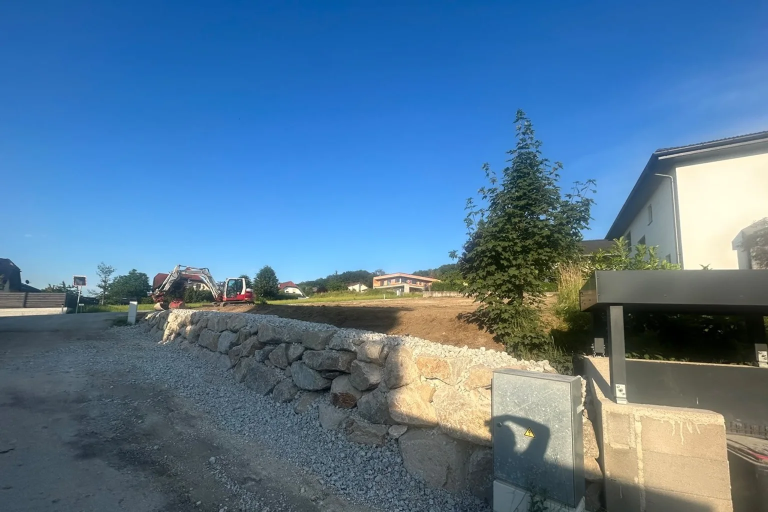 Neu angelegte Natursteinmauer und vorbereitete Gartenfläche bei einem Wohnhaus